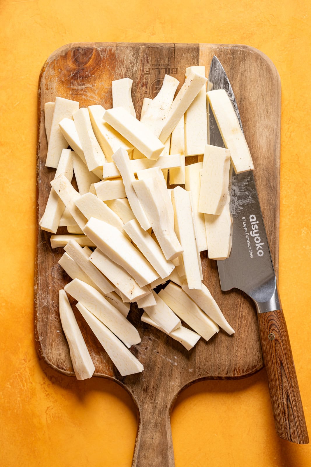 Sliced Yucca on a cutting board with a knife.