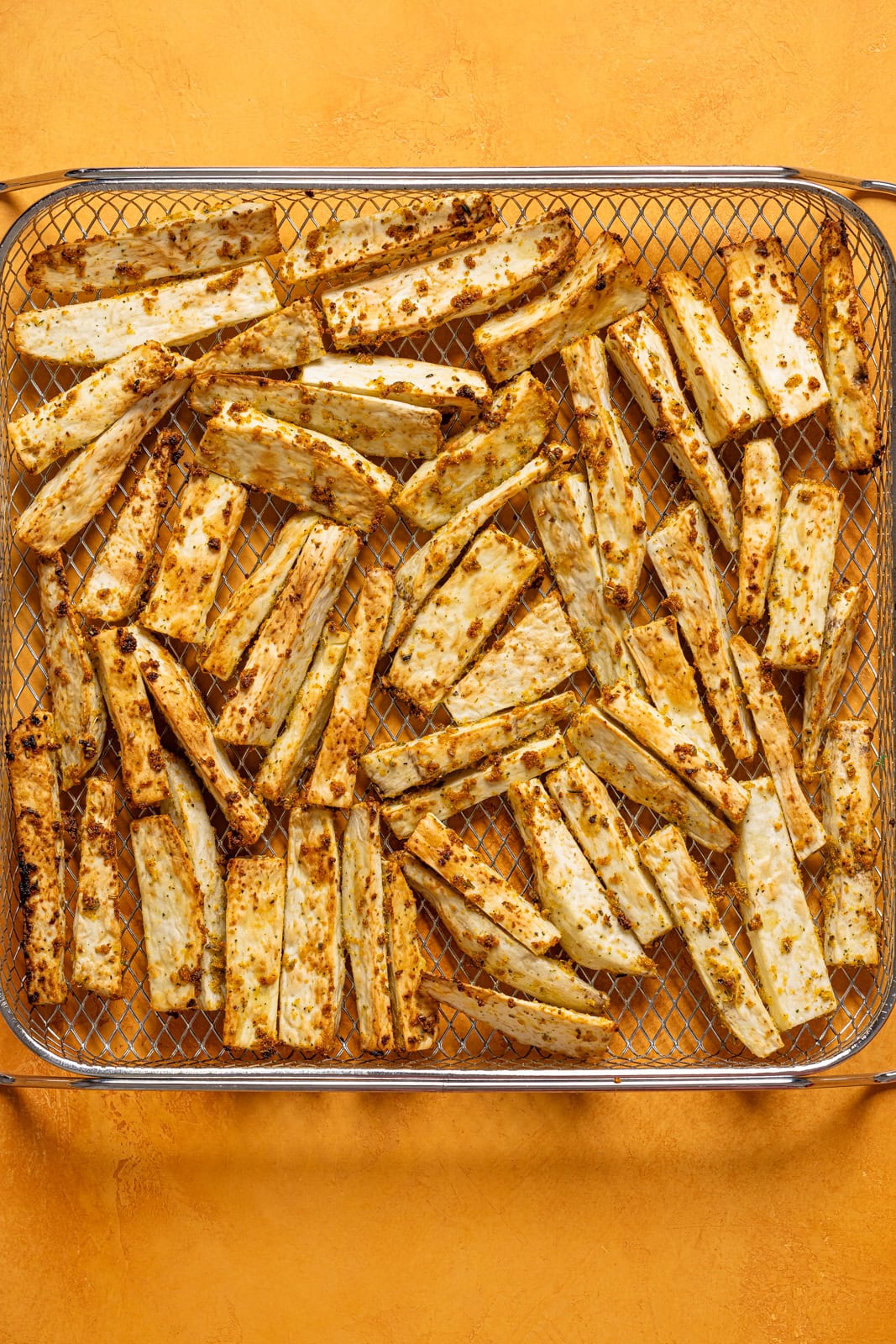 Air Fried Yucca in a basket on an orange table.