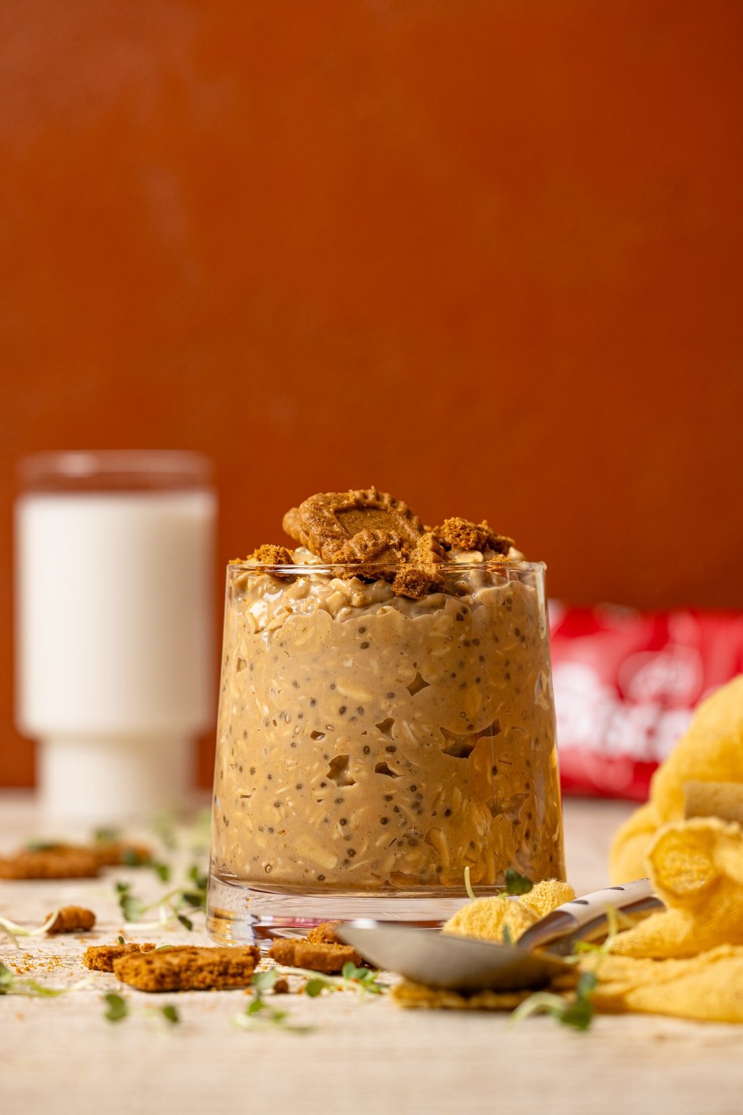 Overnight oats on a white wood table with a glass of milk in the background. 