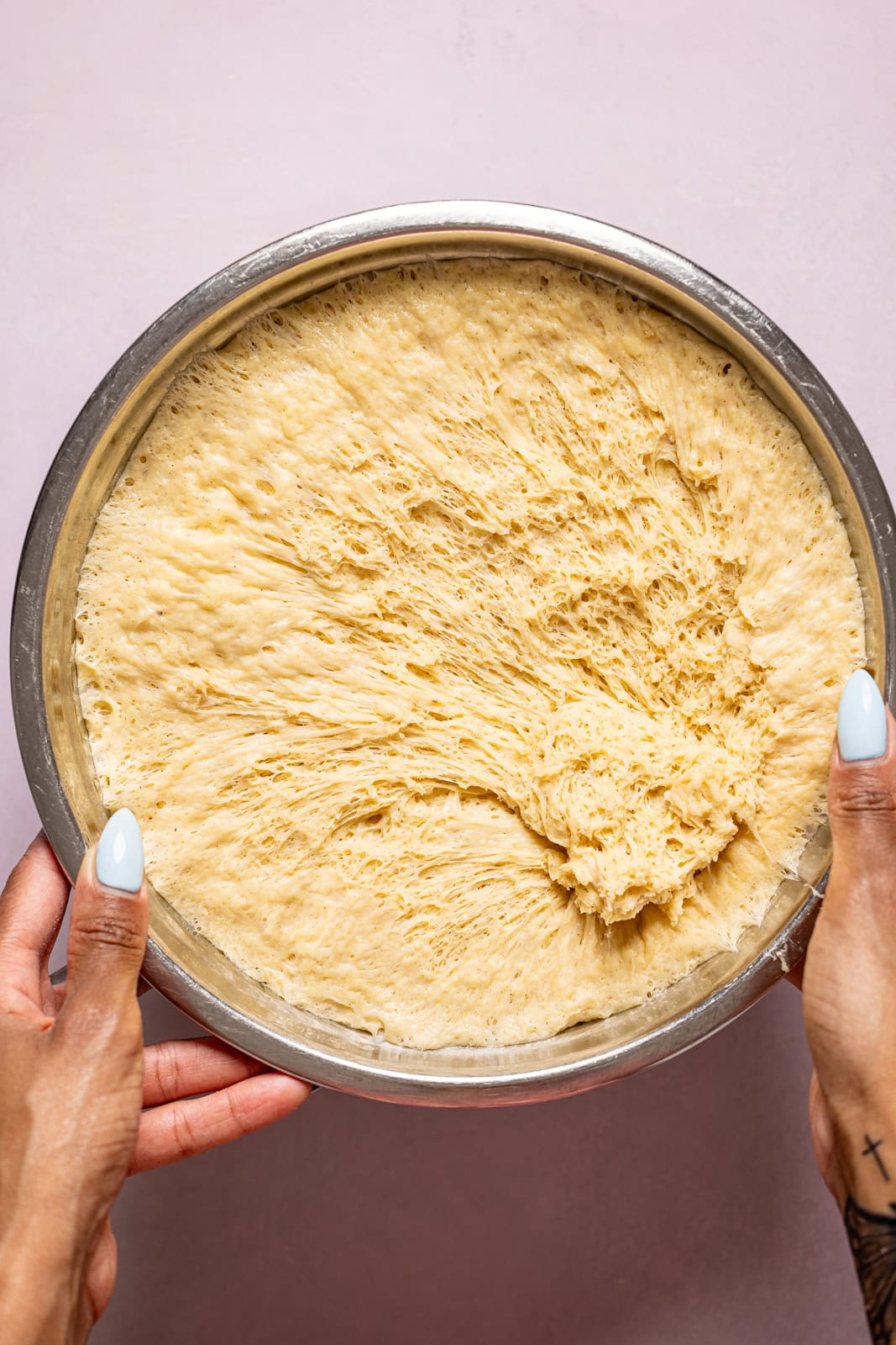 Dough doubled in size after rising in a silver bowl.