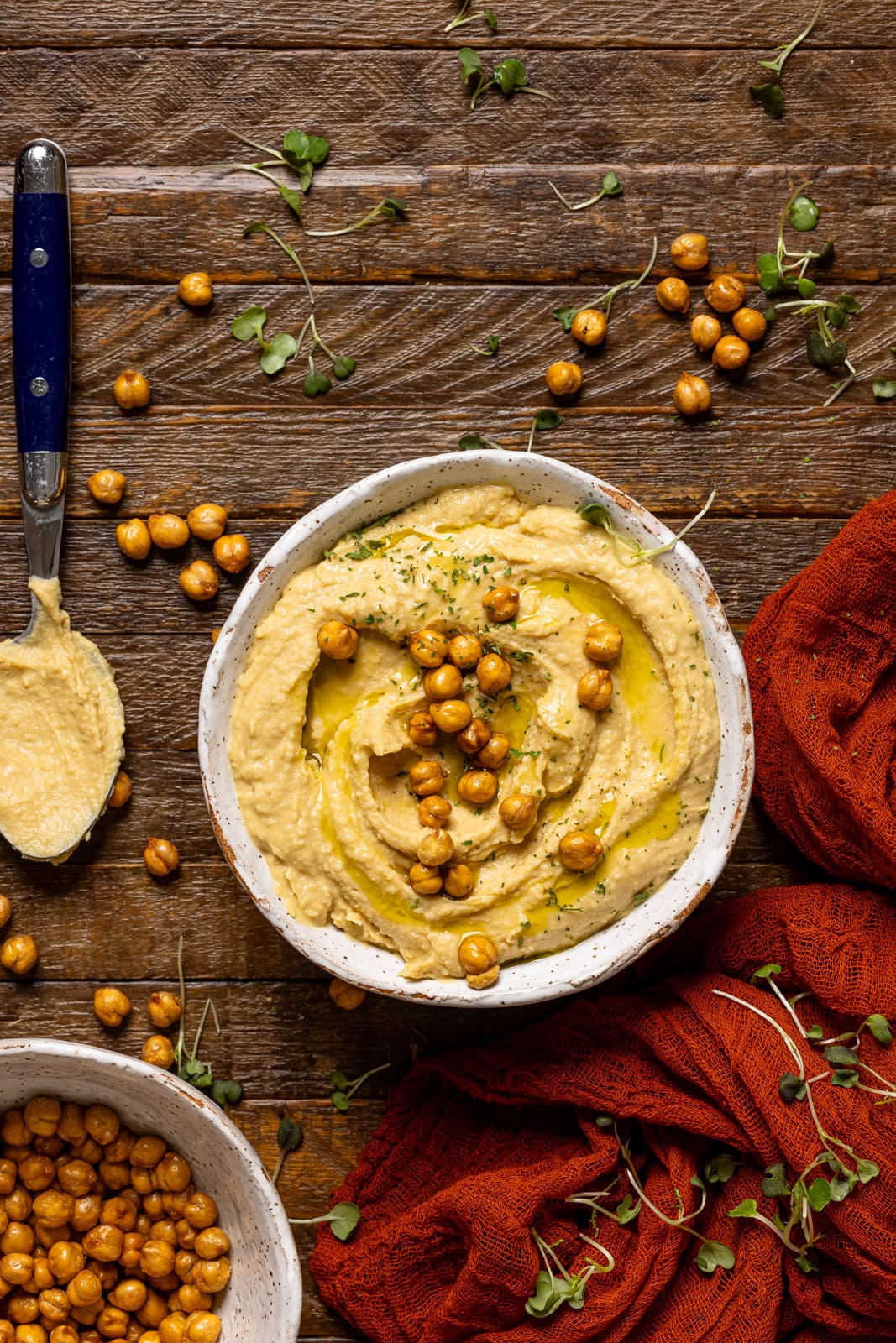 Bowl of hummus with a spoon and chickpeas.