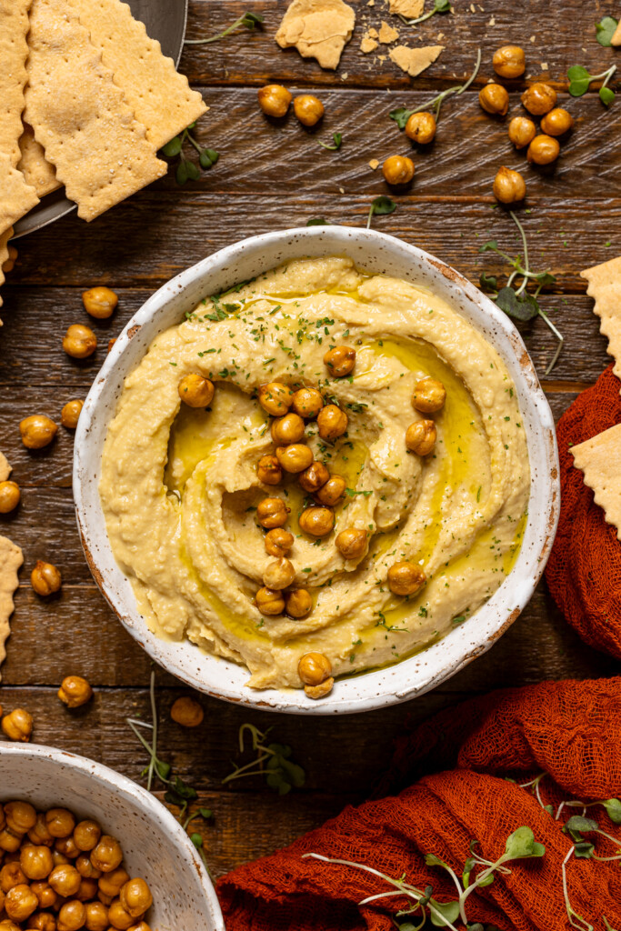 Bowl of hummus on a brown wood table.
