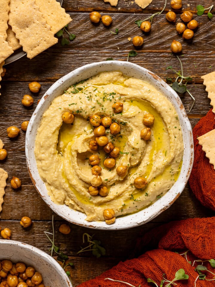 Bowl of hummus on a brown wood table.