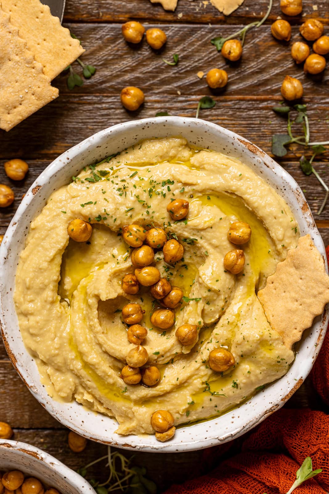 Up close shot of hummus in a bowl with chickpeas and crackers. 