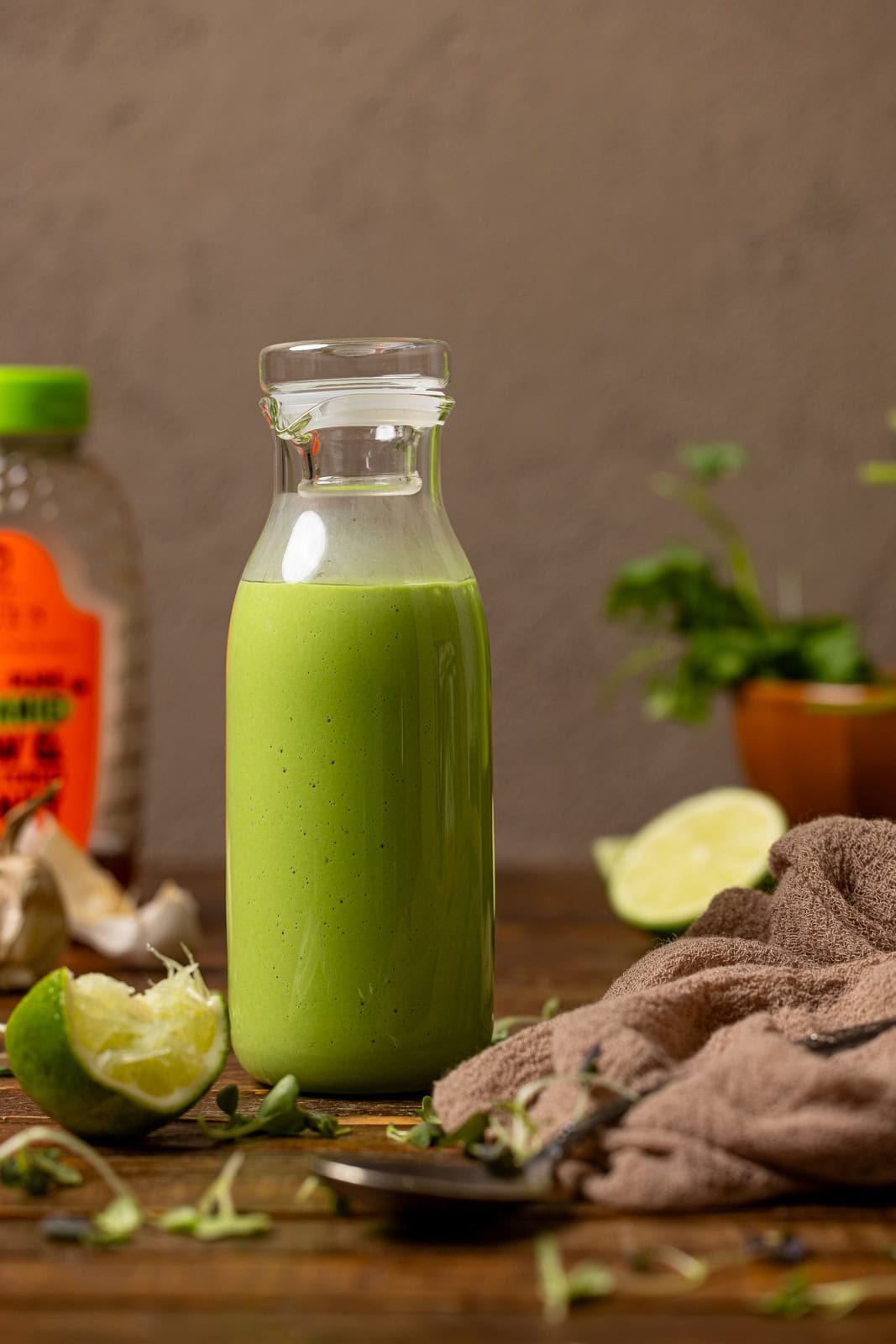 Green dressing in a jar with lime and honey in the background.