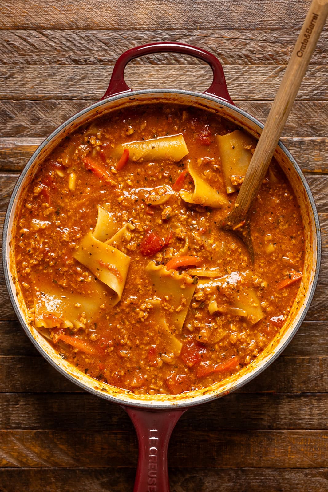 Lasagna soup in a pot with a wooden spoon.