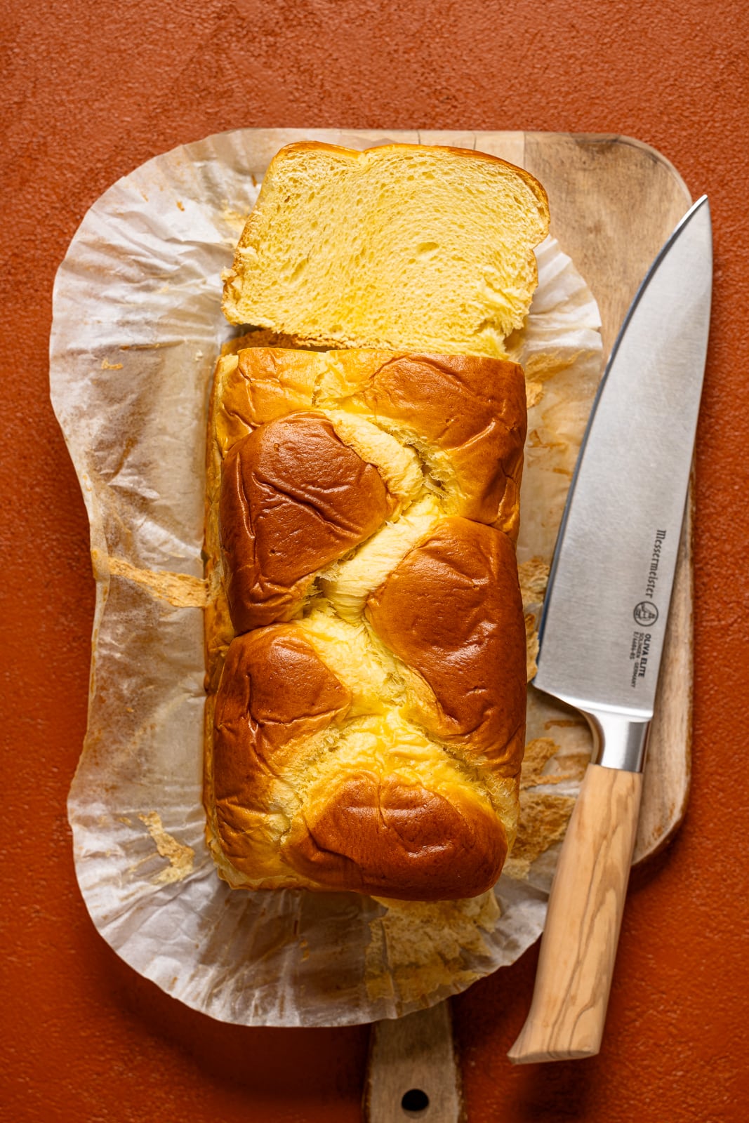 Brioche bread sliced on a cutting board with a knife.