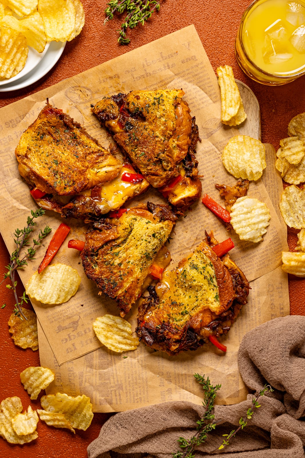 Grilled cheese sandwiches on parchment paper with chips and a drink.