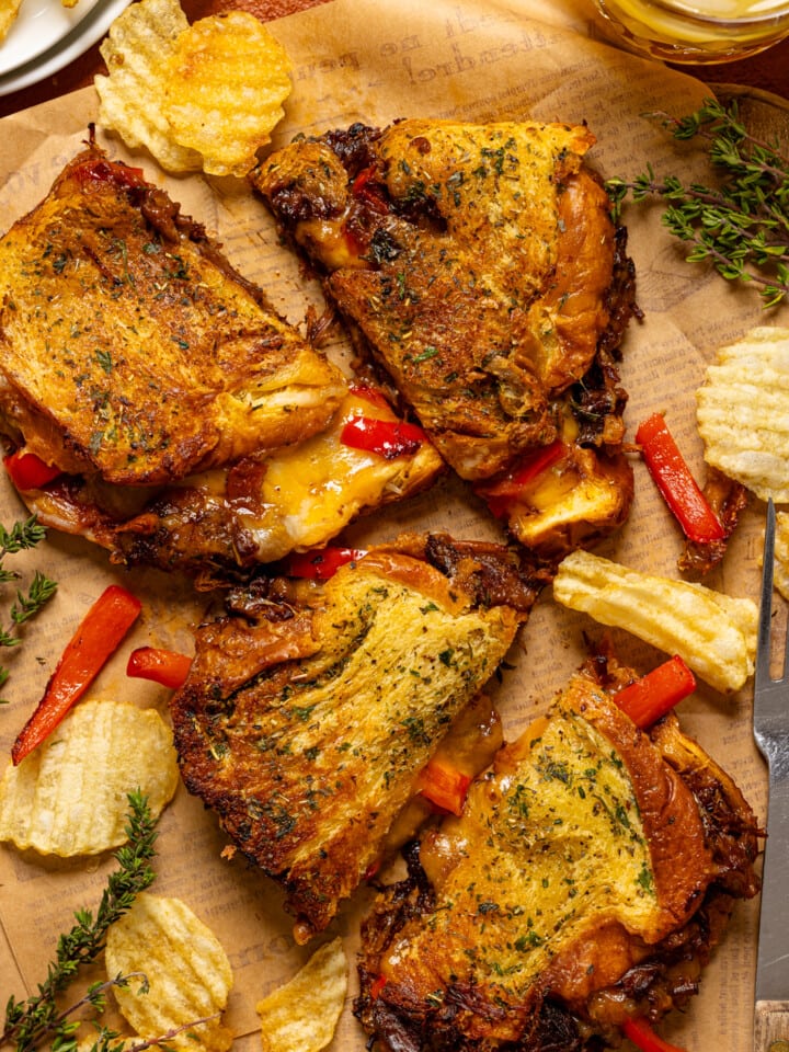 Sandwiches on parchment paper with chips and a drink.