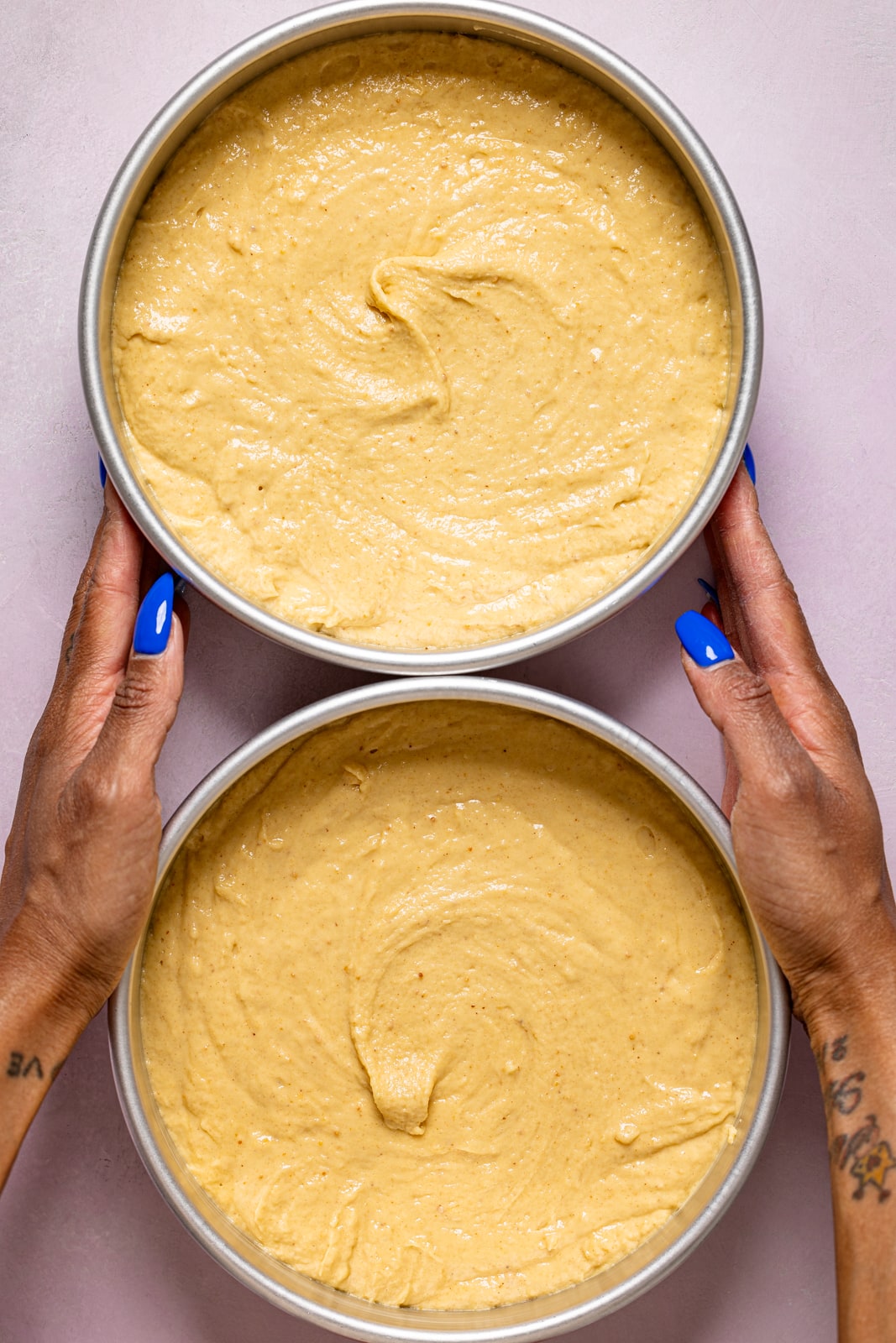 Two cake pans with batter being held.