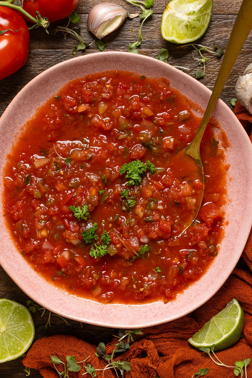 Pink bowl with salsa and a spoon with lime.