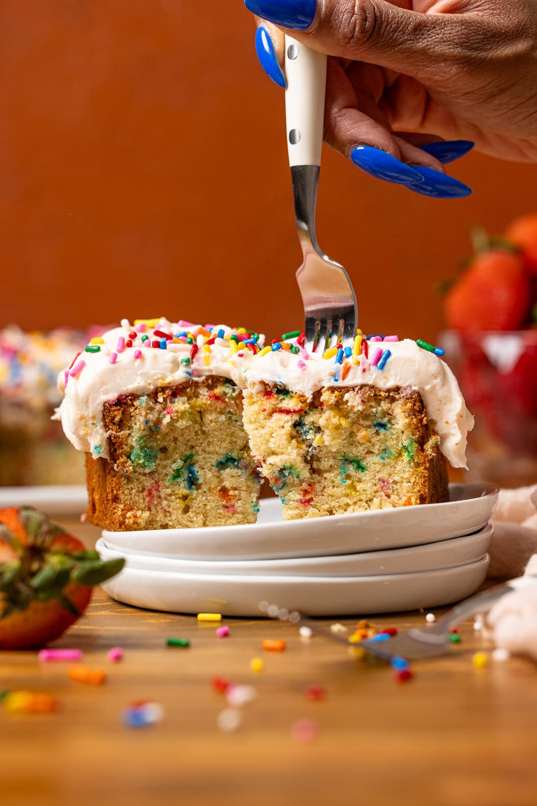 Cake slices on a stack of plates being poked with a fork.