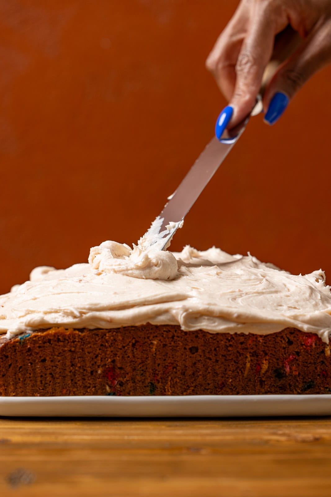 Cake being frosted with a spatula. 