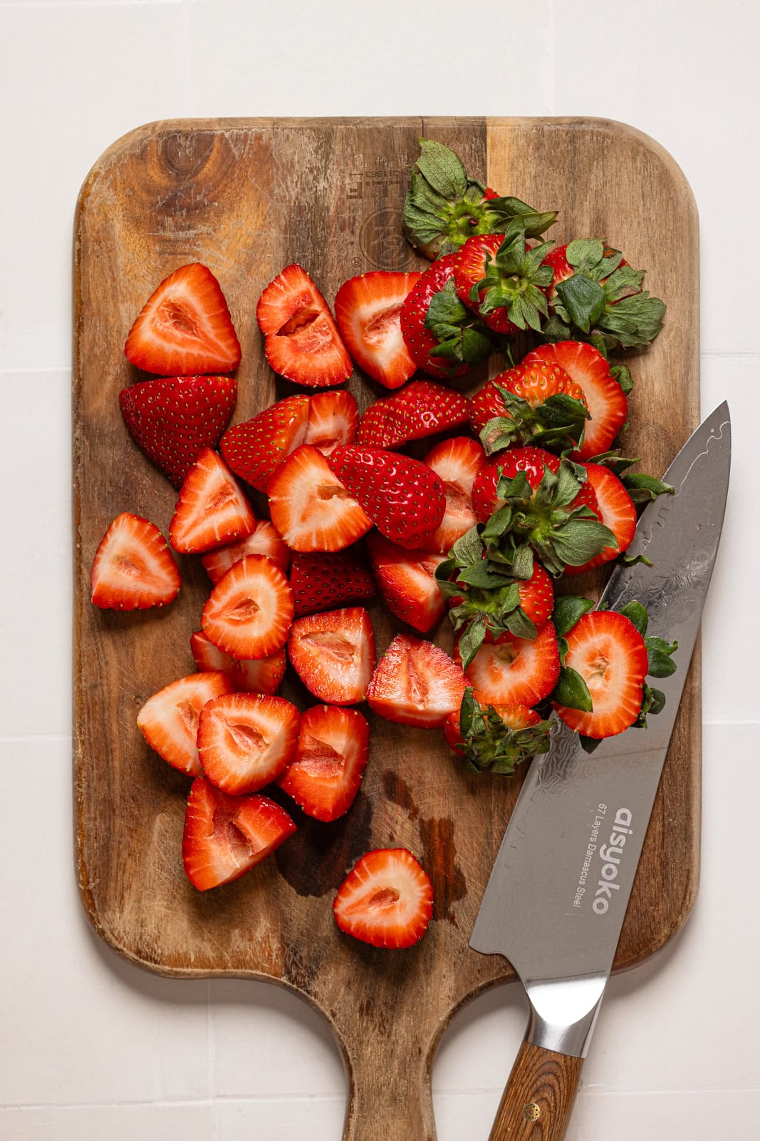 Sliced strawberries on a cutting board with a knife.