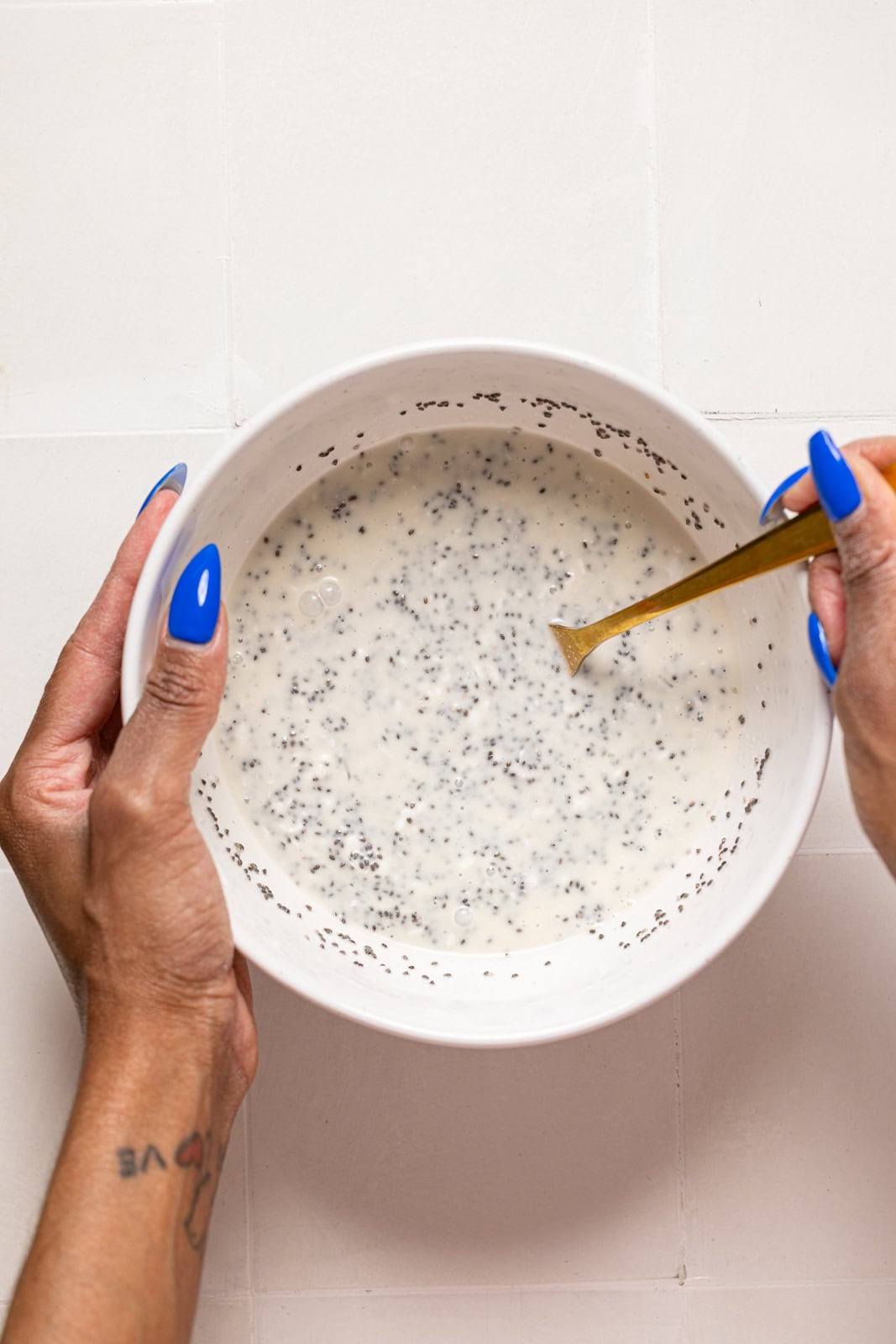 Chia pudding being stirred in a white bowl.