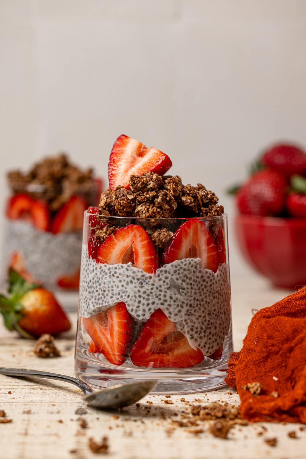 Chia pudding in two glasses with strawberries and a spoon.