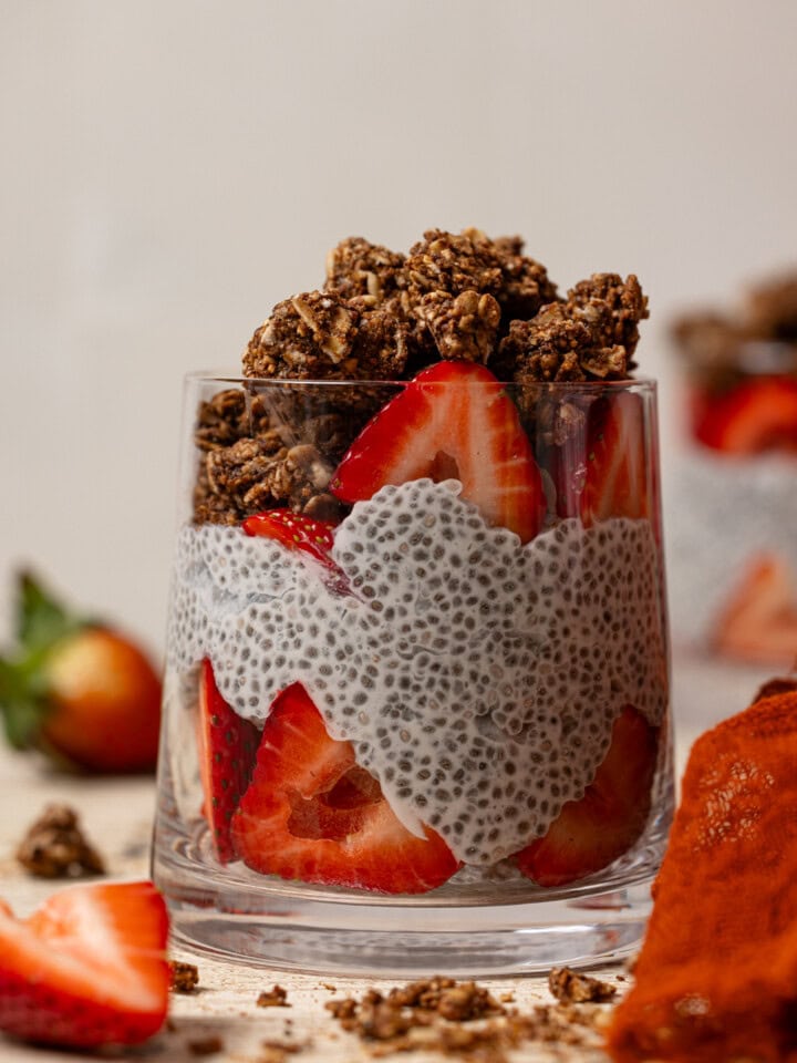 Up close shot of chia pudding in a glass with strawberries and granola.
