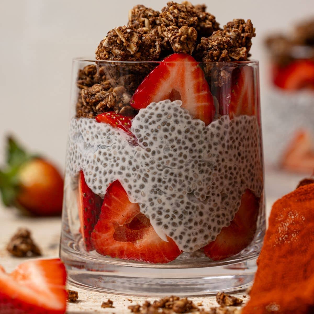 Up close shot of chia pudding in a glass with strawberries and granola.