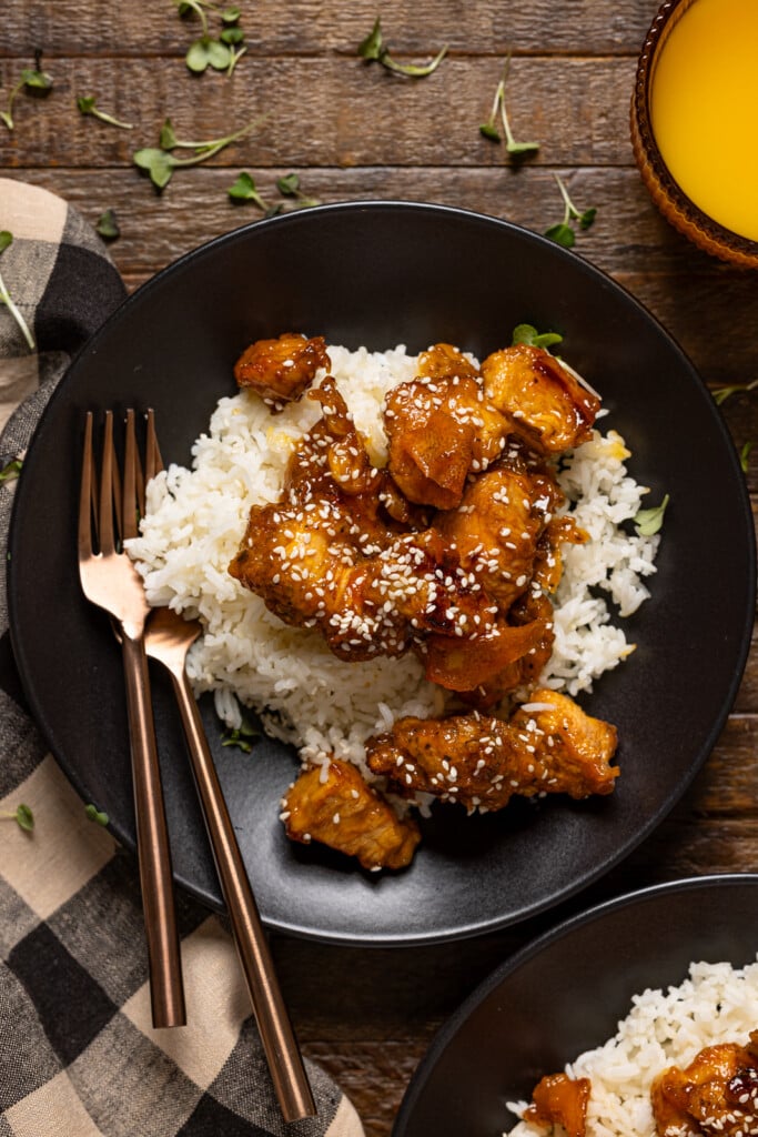 Two plates on Orange chicken with forks.