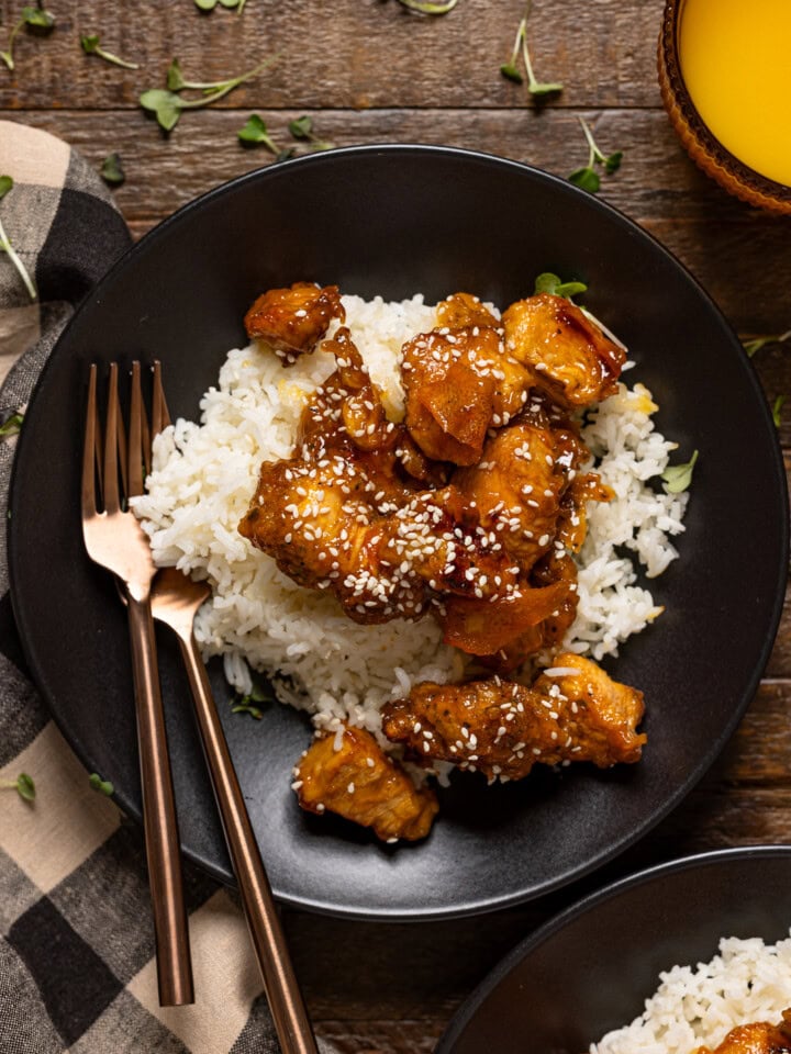 Two plates on Orange chicken with forks.