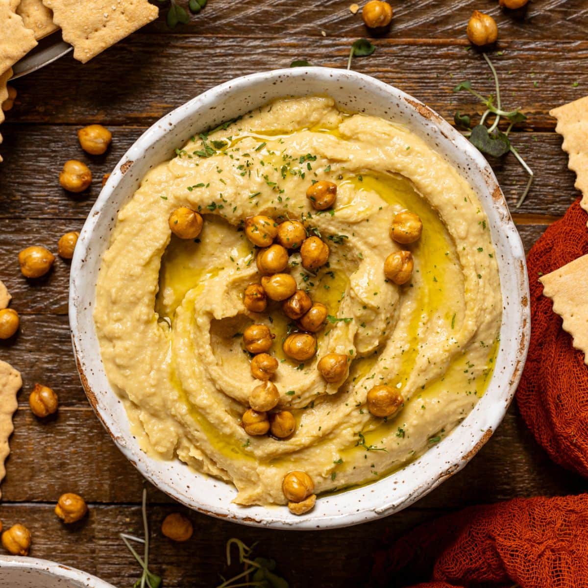 Bowl of hummus on a brown wood table.