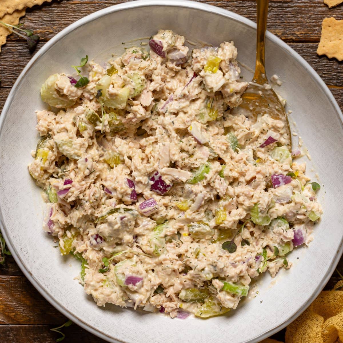 Tuna salad in a plate with a spoon and crackers.