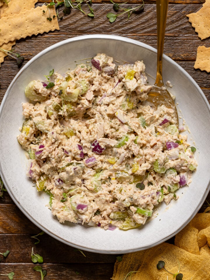 Tuna salad in a plate with a spoon and crackers.
