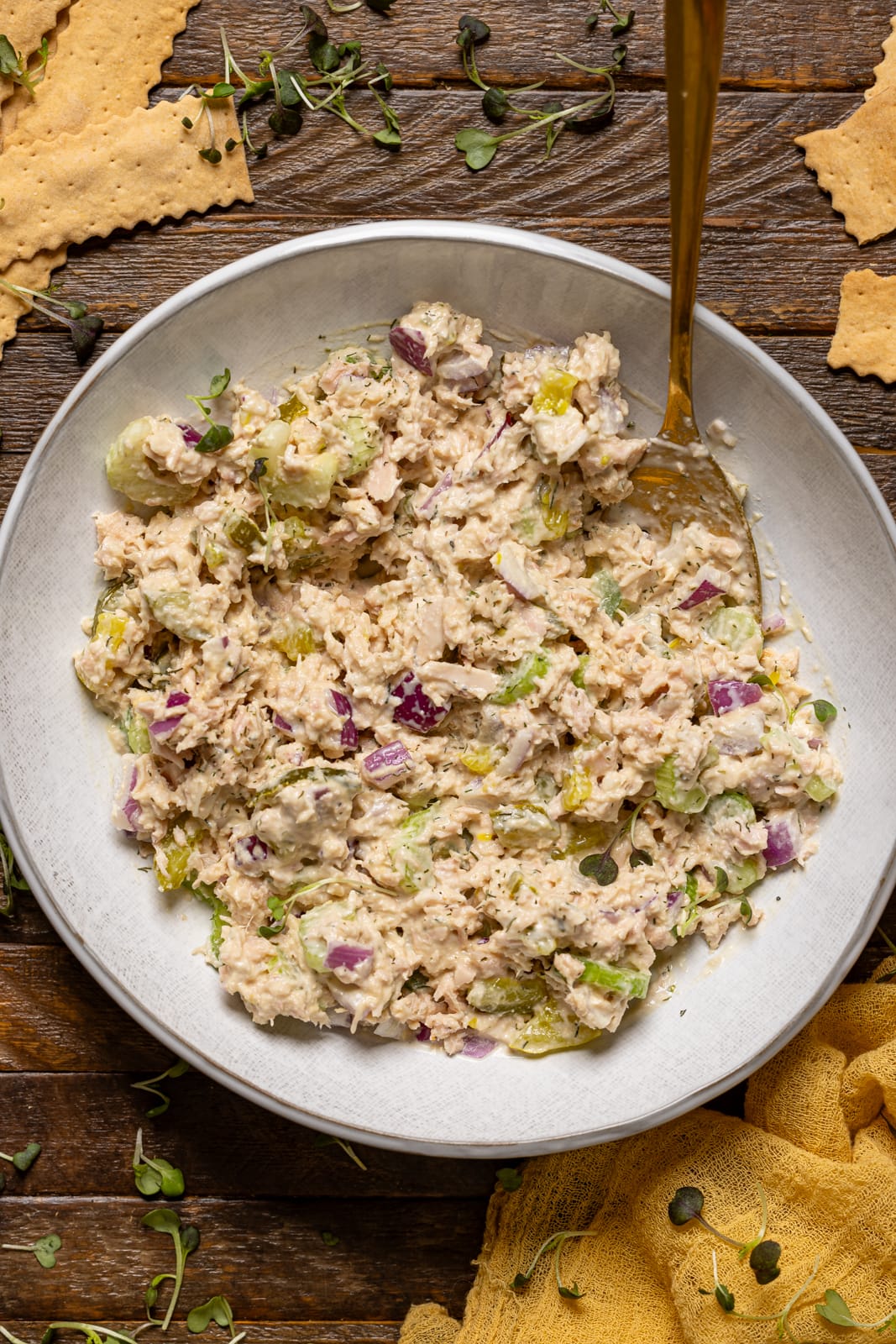 Tuna salad in a plate with a spoon and crackers.