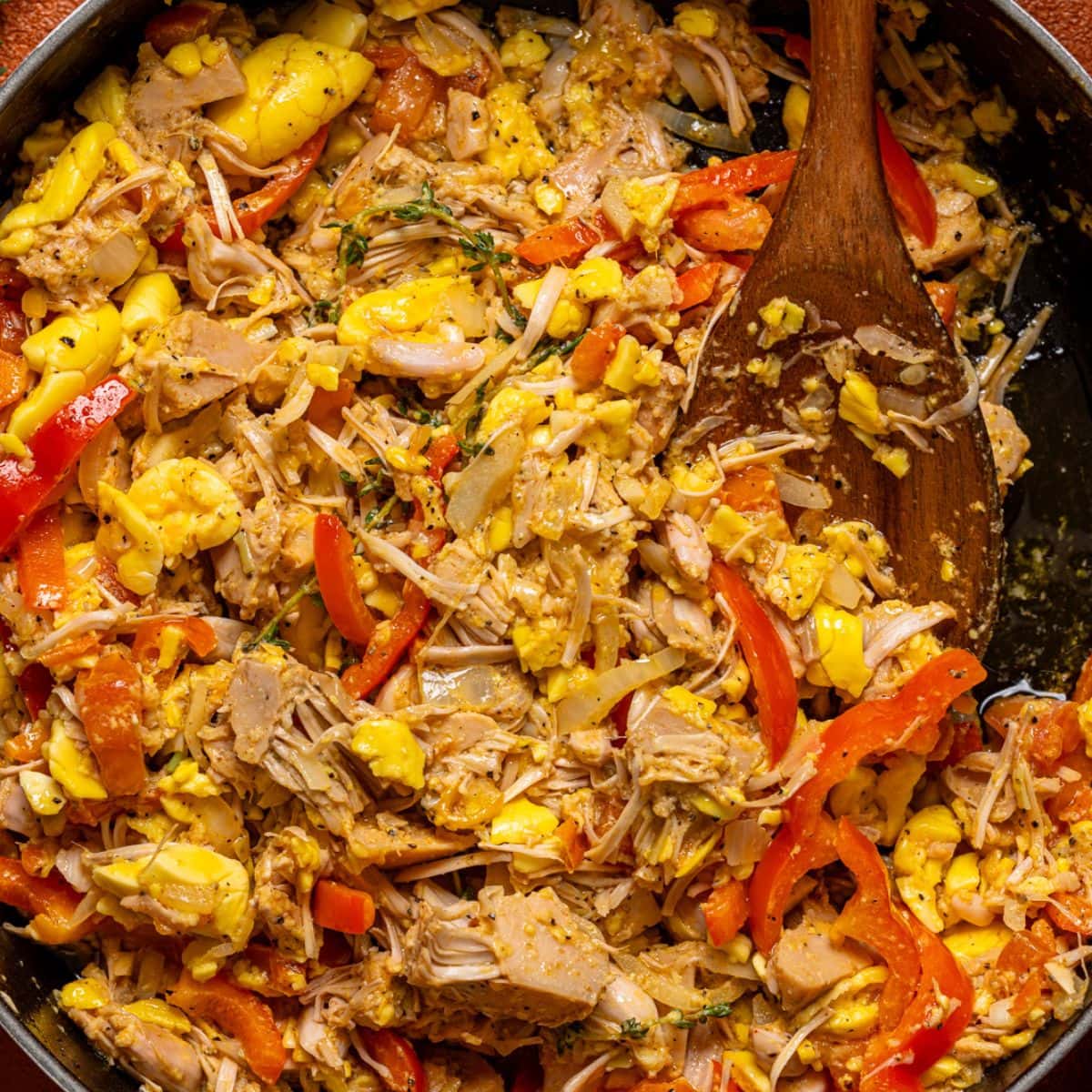 A pot full of ackee and saltfish with a wooden spoon.