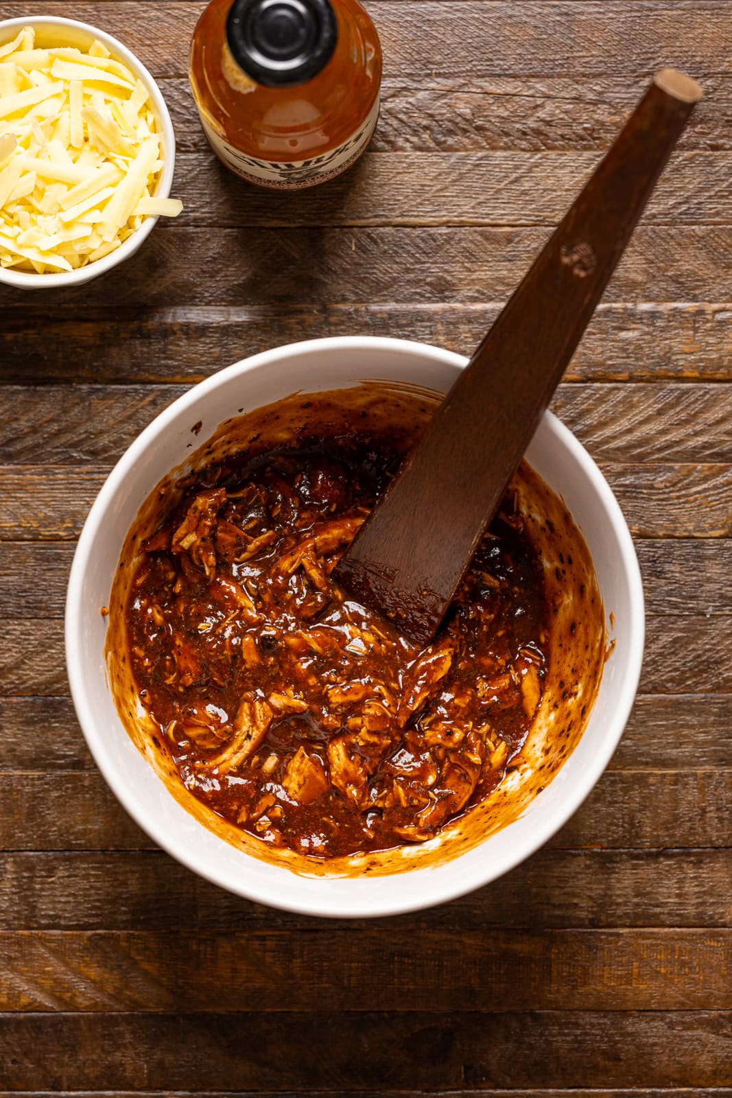 BBQ chicken in a bowl with a wooden spoon.