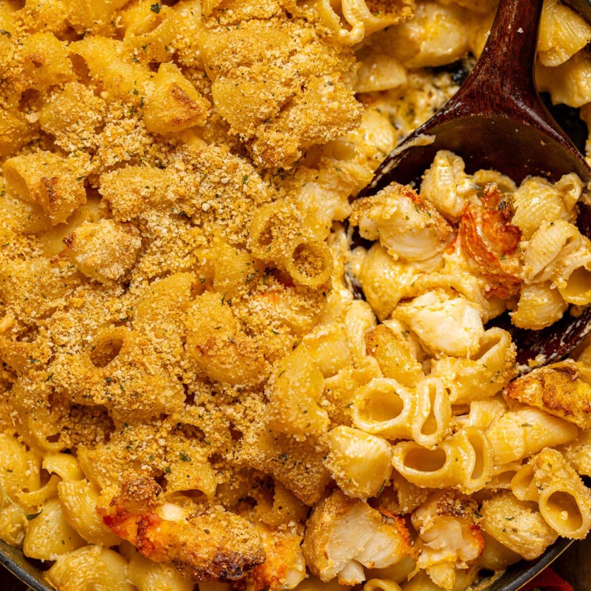 Up close shot of baked mac and cheese with a wooden spoon.