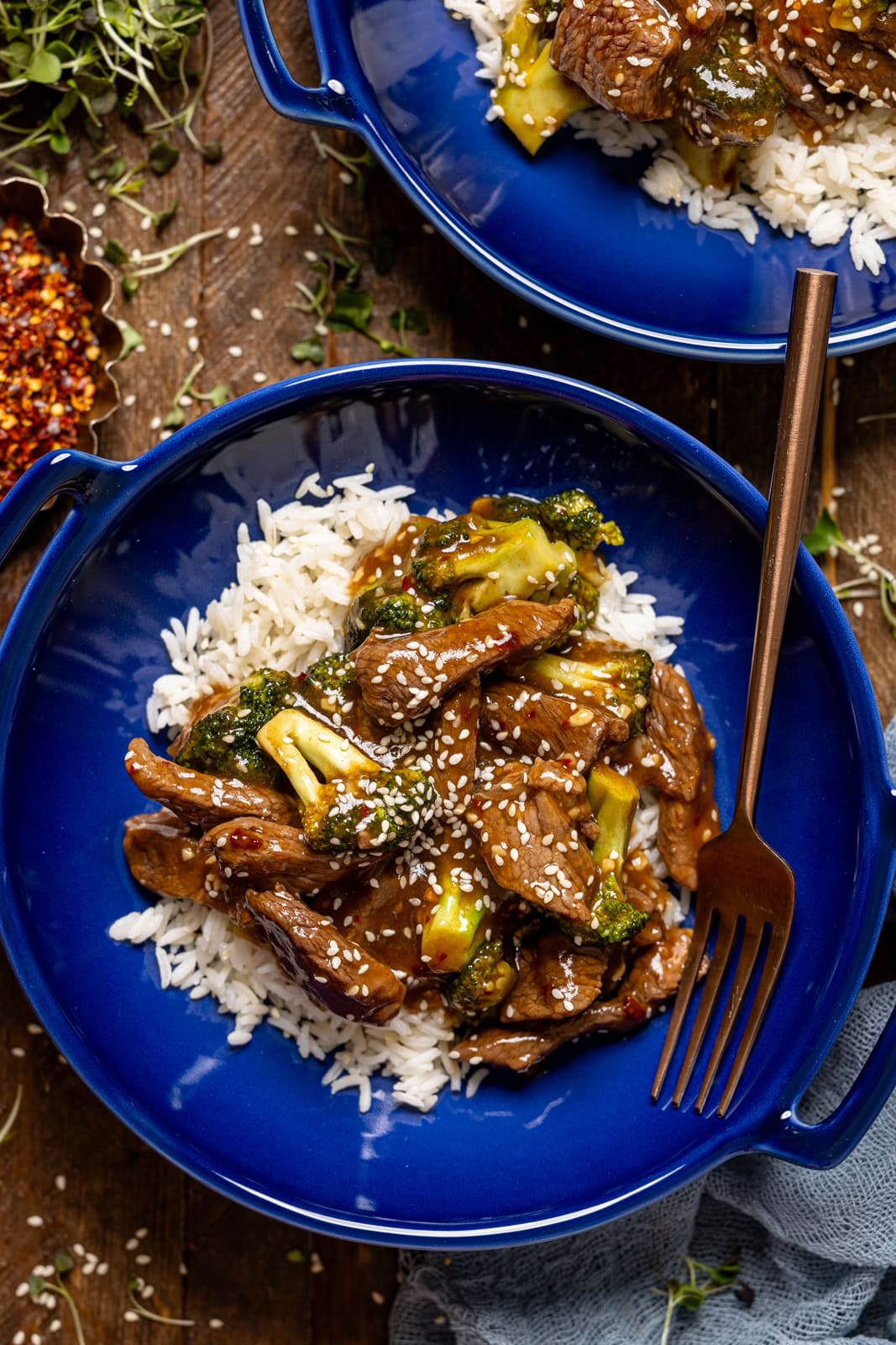 Beef and broccoli in two plates with a fork.