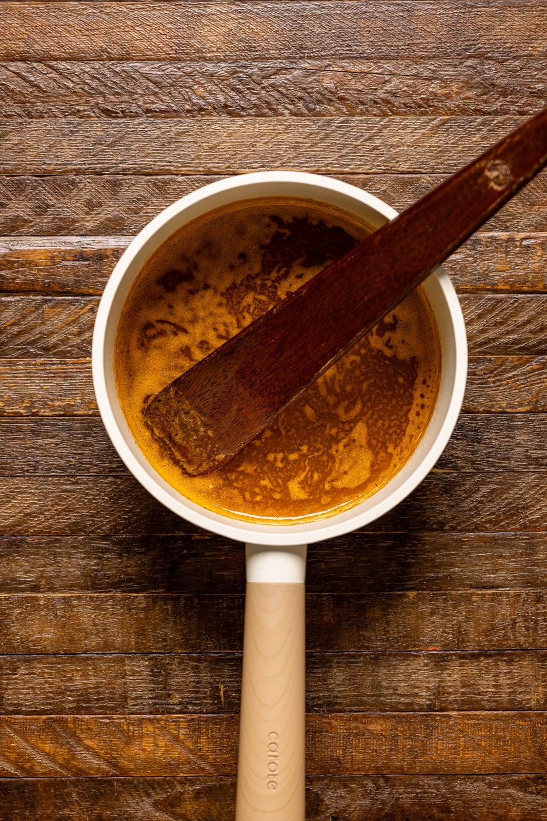 Seasoned melted butter in a pot with a wooden spoon.