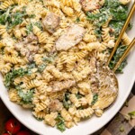 Chicken pasta salad on a platter with two spoons.