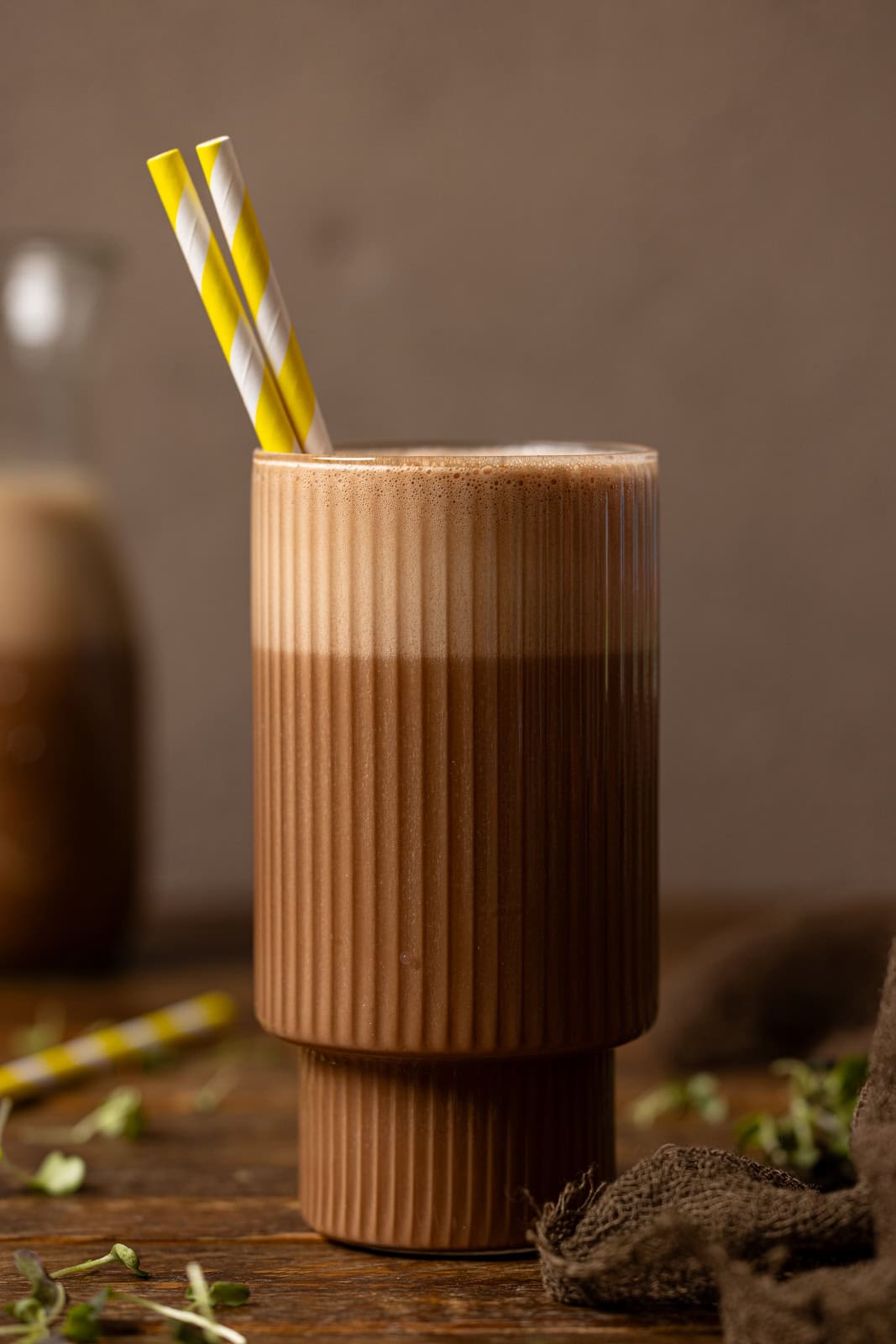 Glass of chocolate milk with yellow stripe straws. 