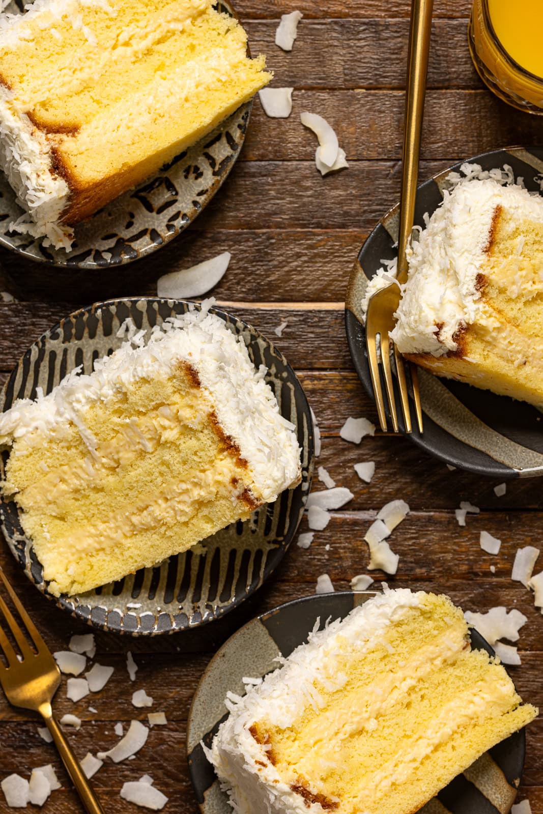 Four slices of cakes on a plates with a fork on a brown wood table.