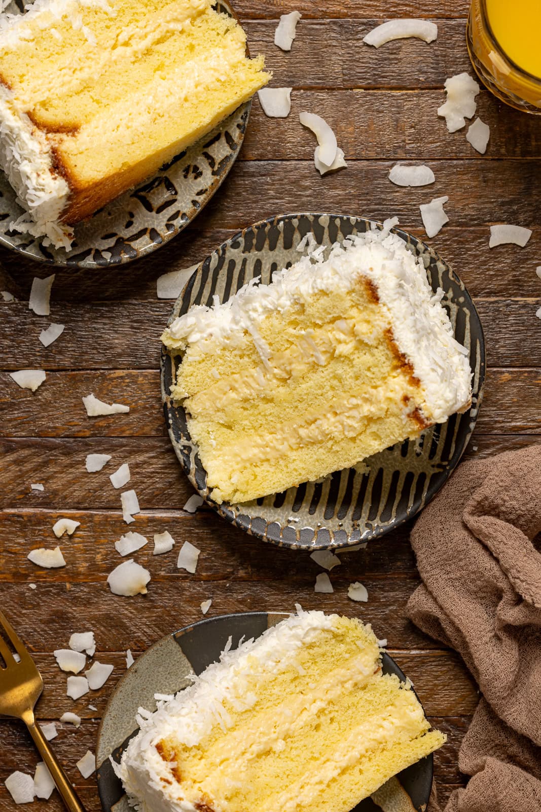 Three slices of cake on a plate on a brown wood table.