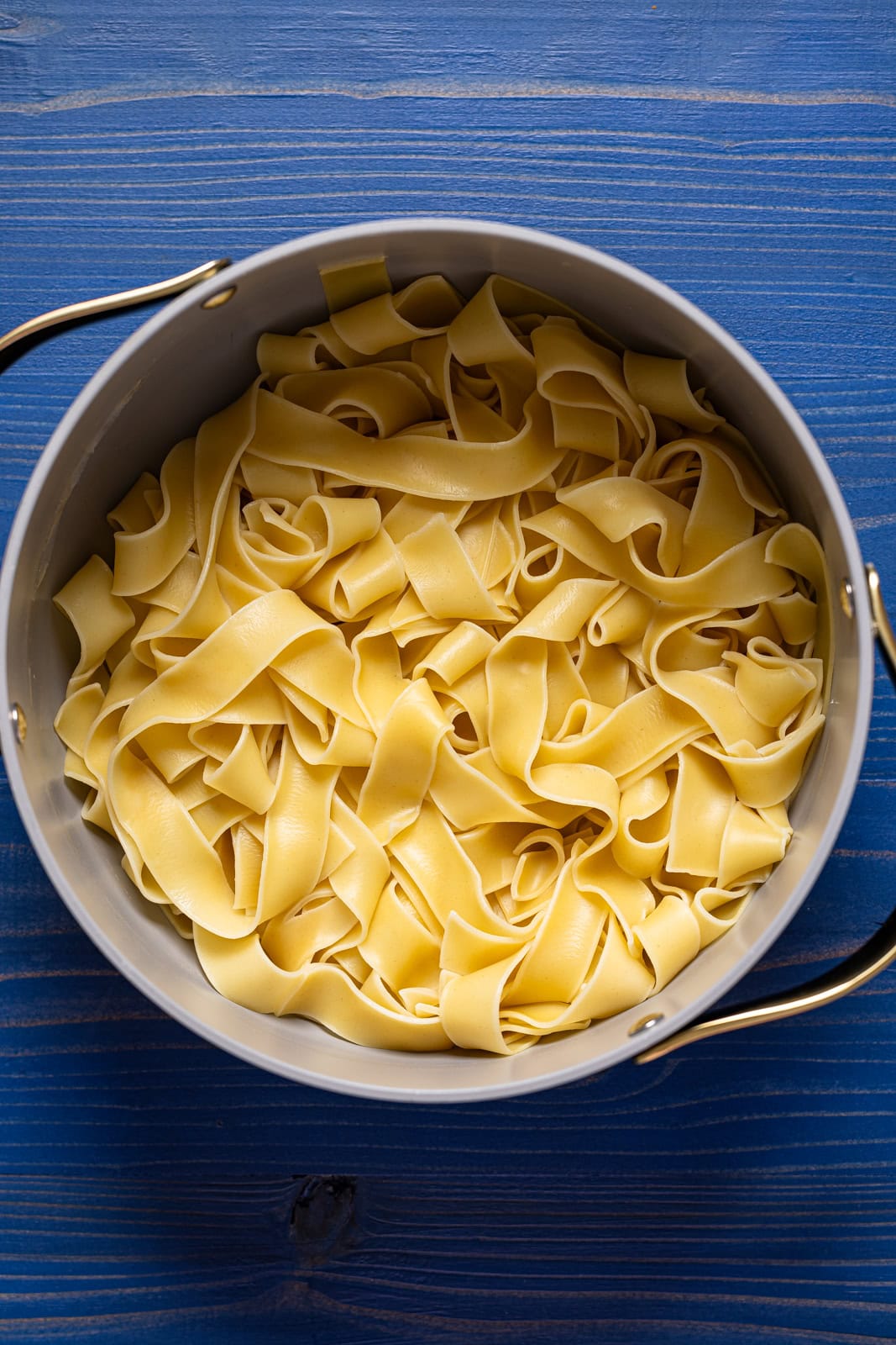 Cooked pasta in a pot on a blue wood table.