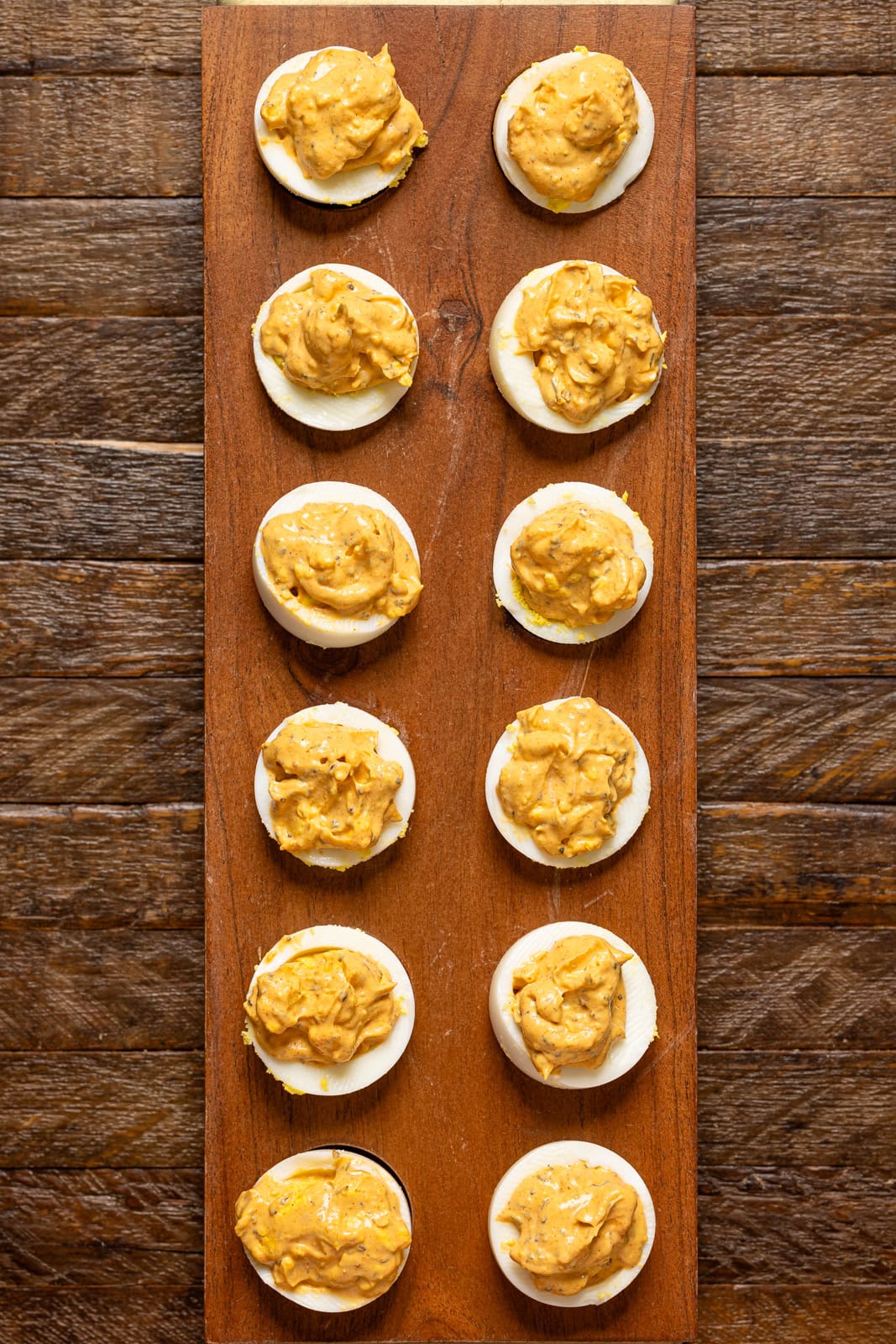 All deviled eggs are lined on a wooden tray.