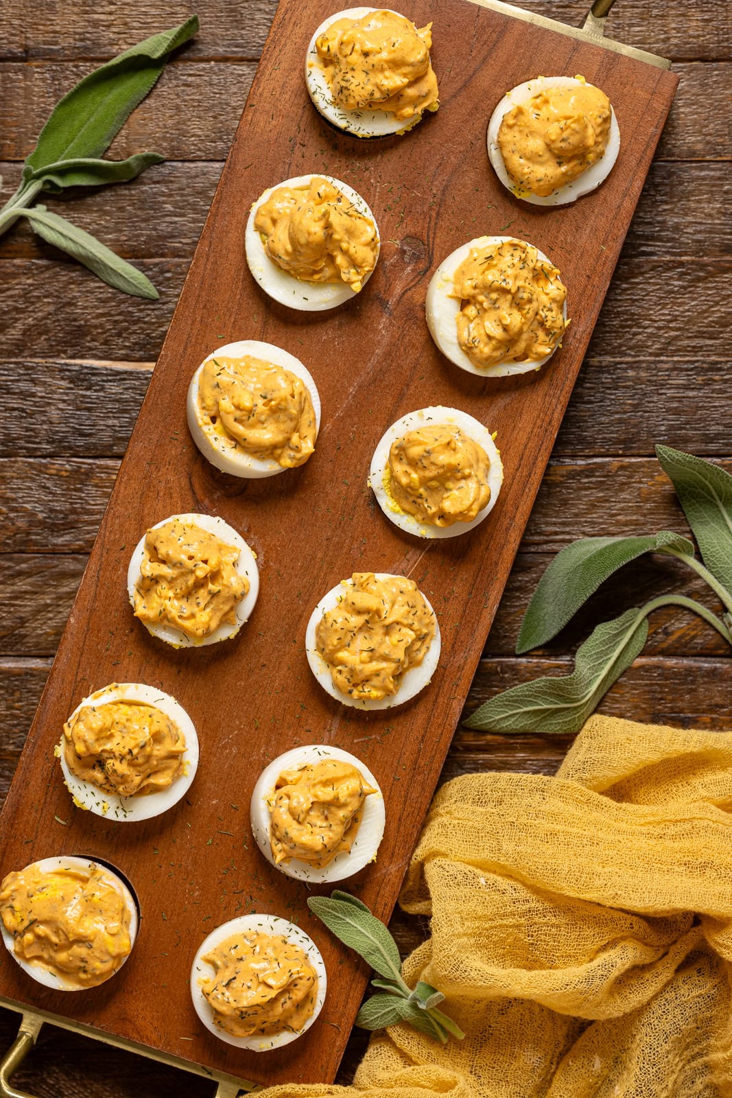 Lined on a wooden tray all eggs with sage leaves and a yellow napkin.