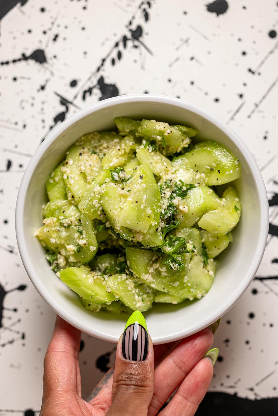 Cucumber salad in a bowl being held.