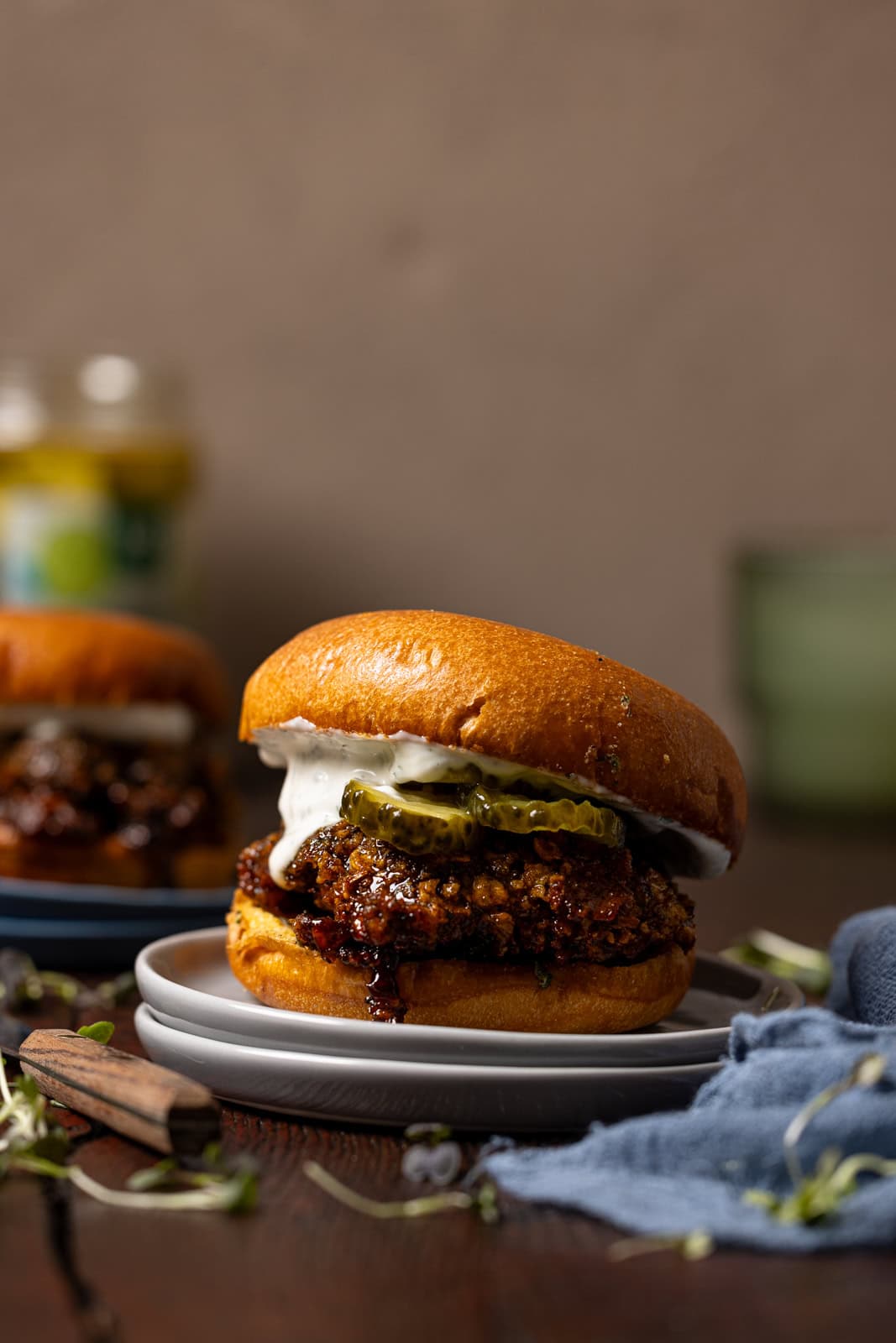 Chicken sandwiches on plates with drinks in the background.