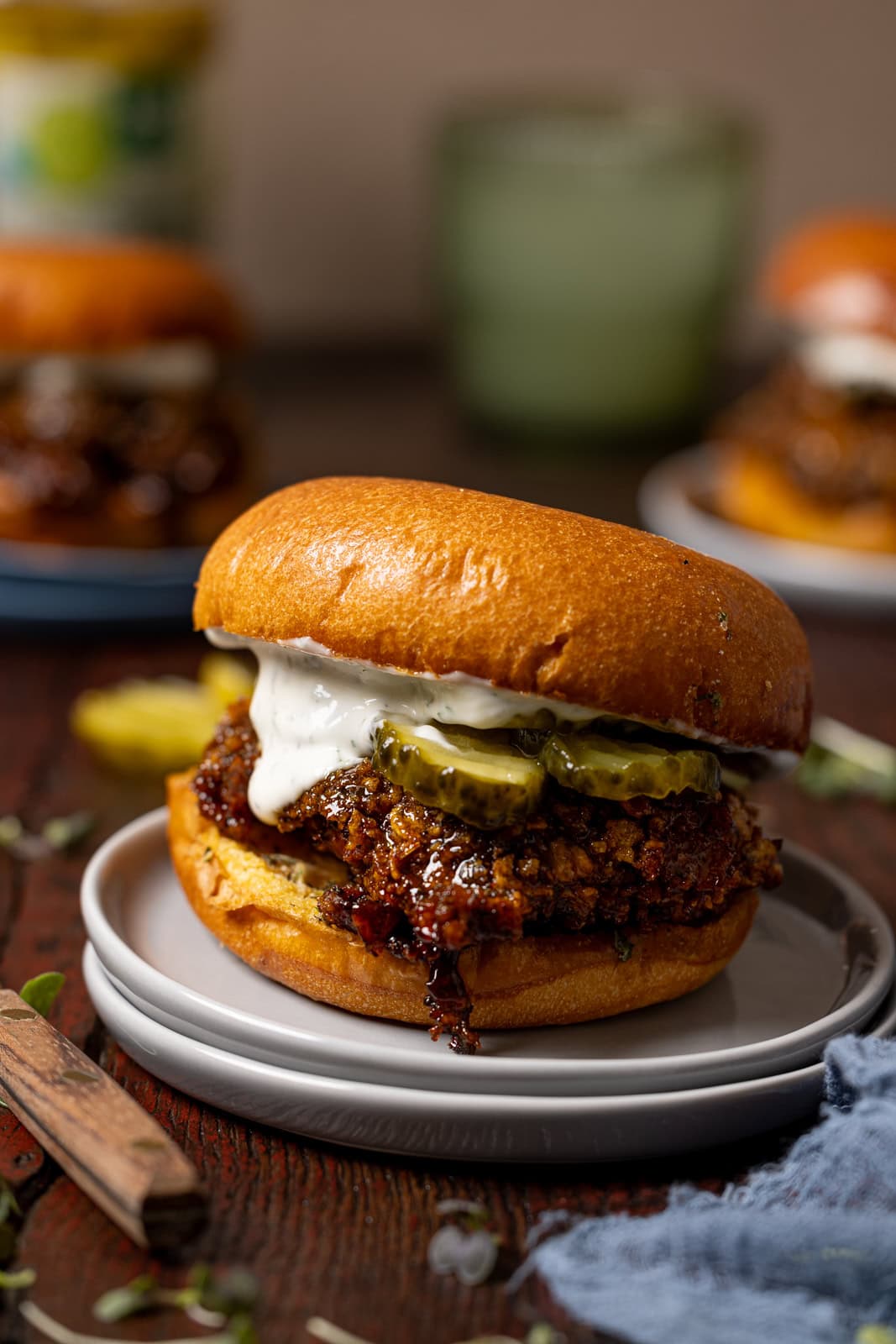 Up close shot of hot honey chicken sandwich on grey plates with sandwiches in background.