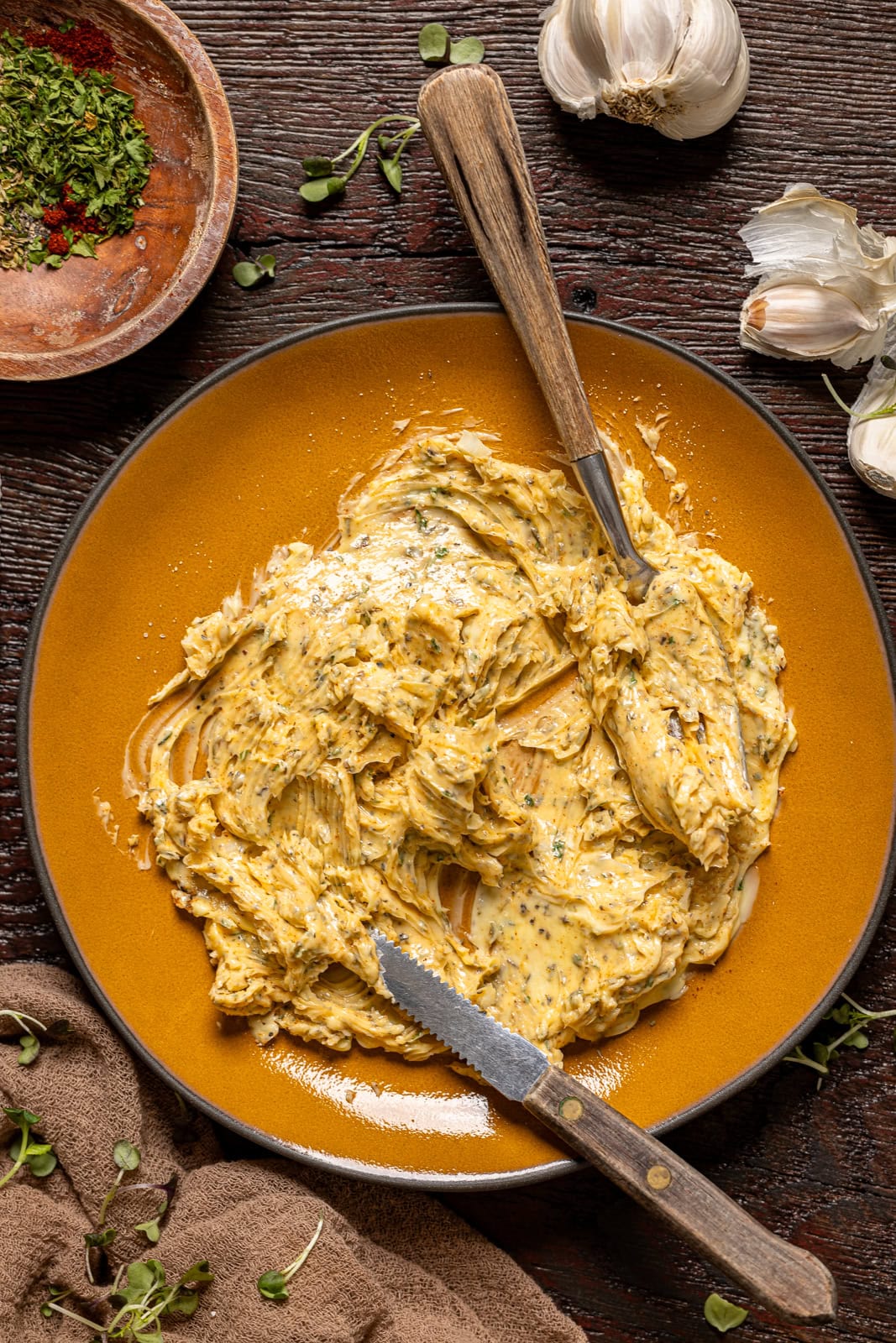 Herb butter on a plate with knives.