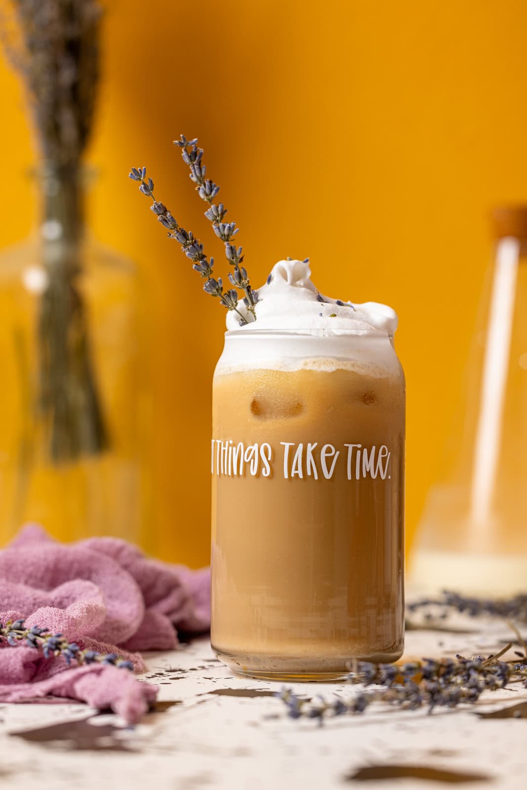 One glass of iced latte with lavender flowers and a yellow background.