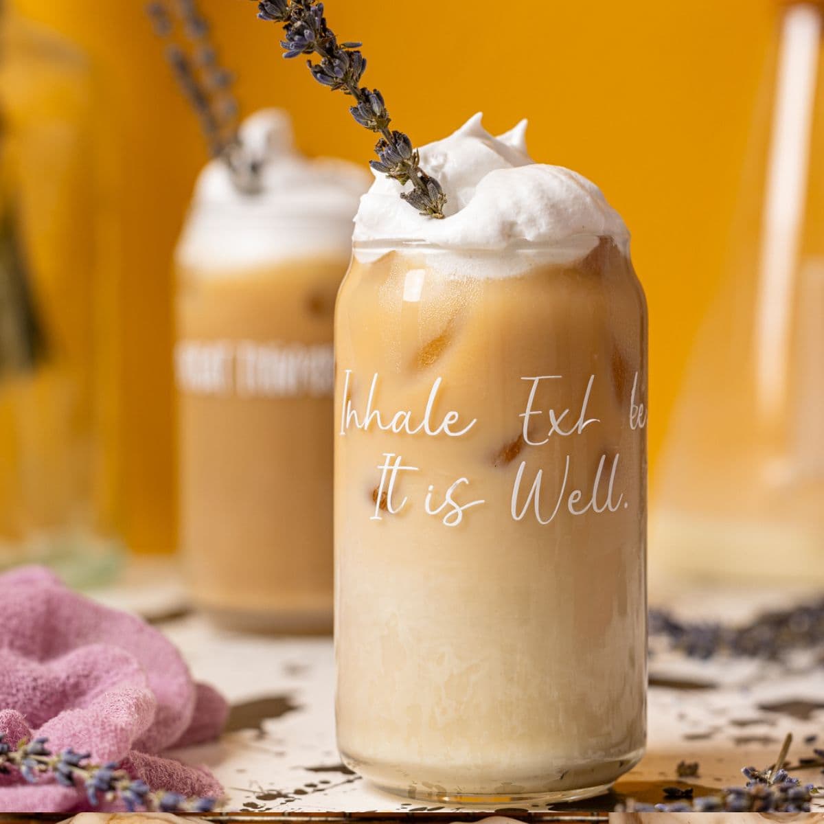 Two glasses of iced lattes with lavender flowers.
