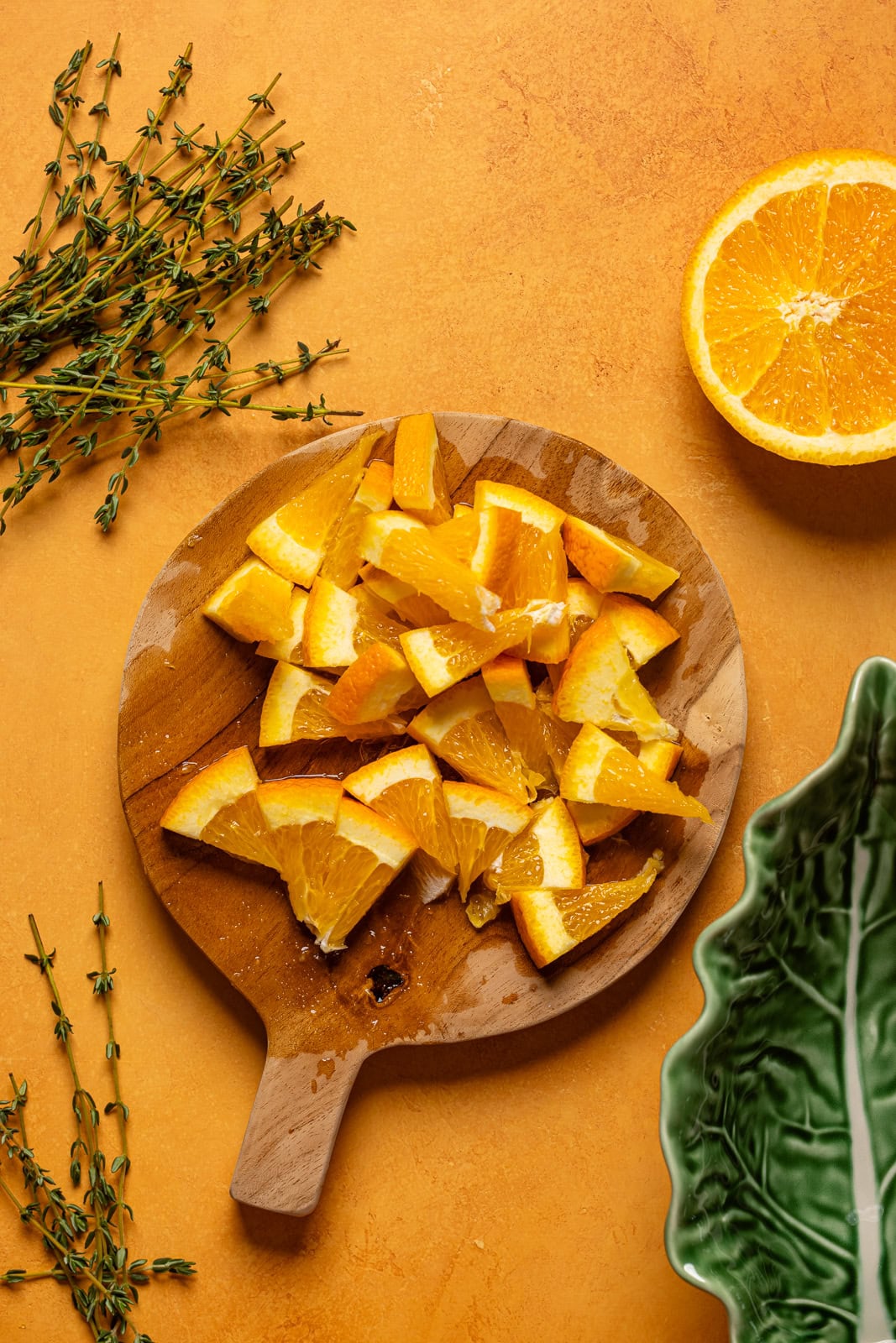Sliced oranges on a cutting board on a orange table.