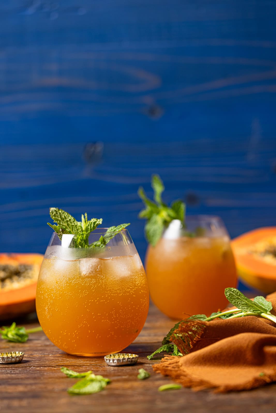 Two glasses of drinks with a navy background and papaya.