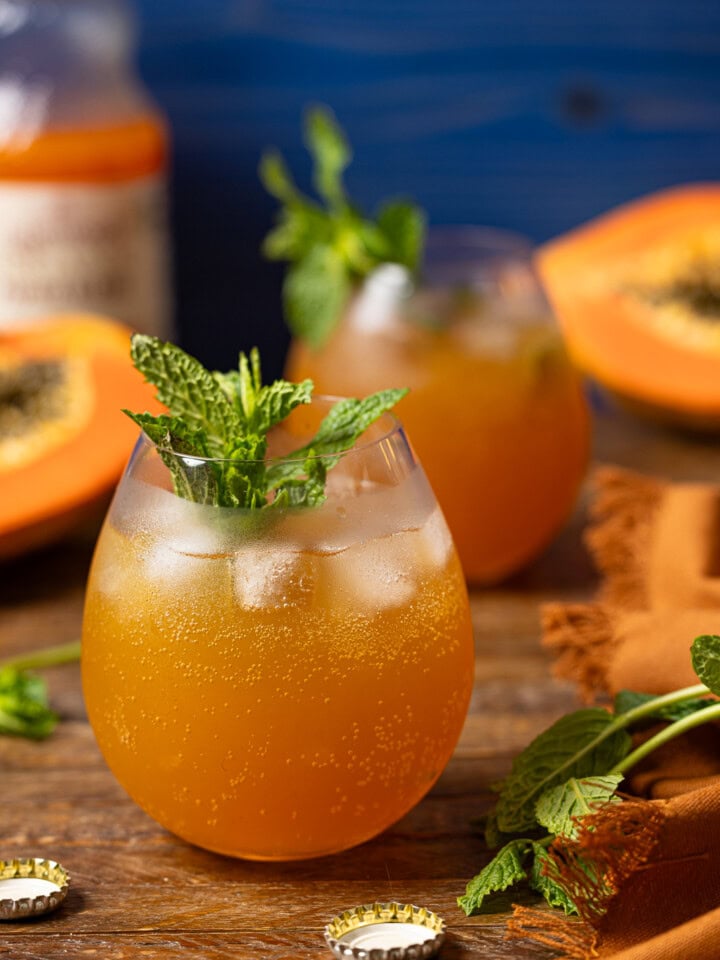 Two glasses of mocktails on a brown wood table with papaya.