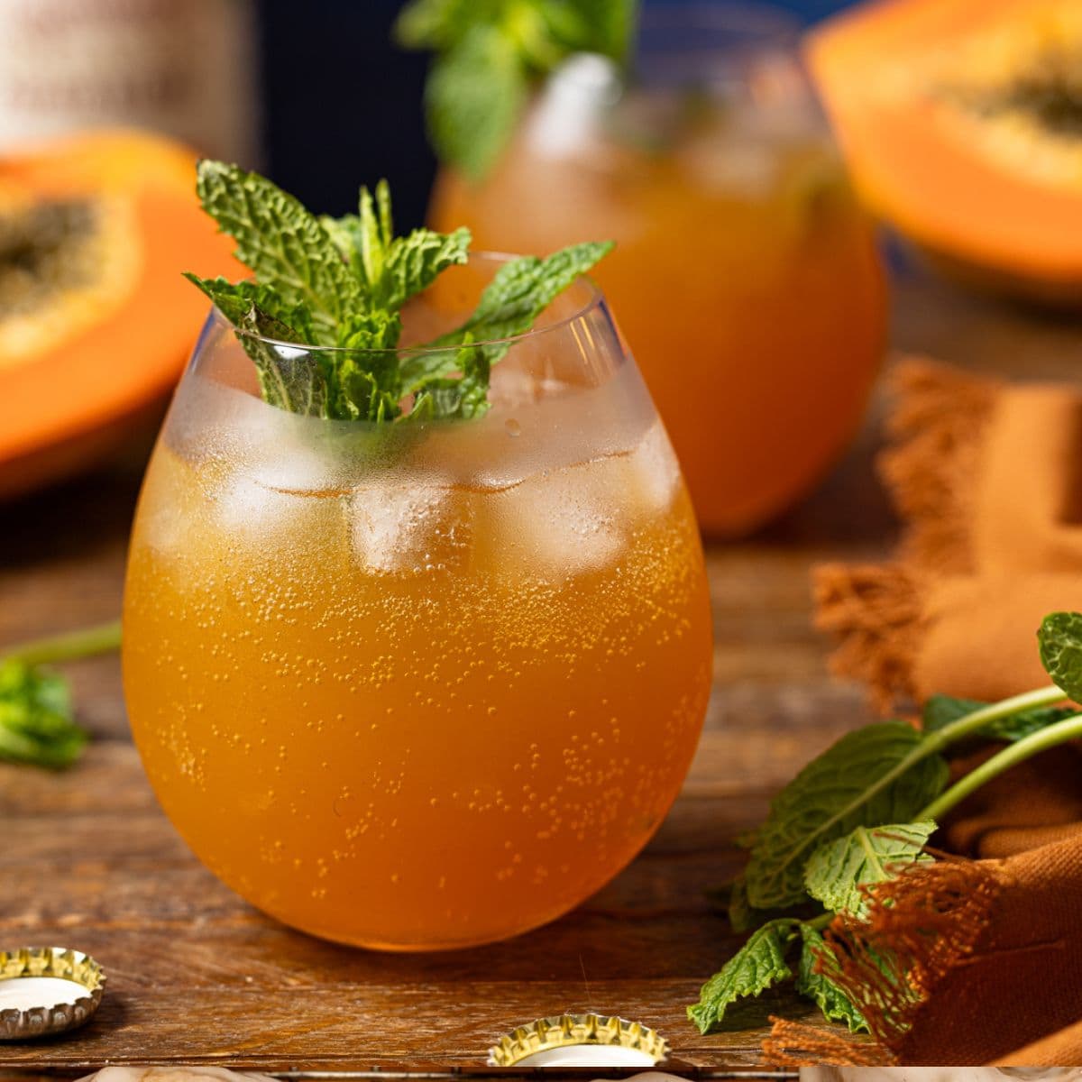Two glasses of mocktails on a brown wood table with papaya.